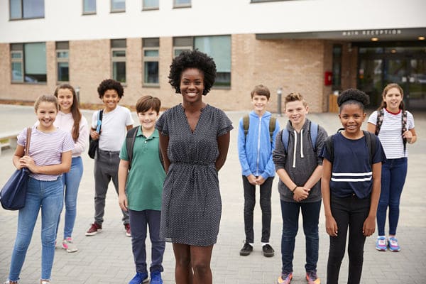 kids and teacher standing outside a building